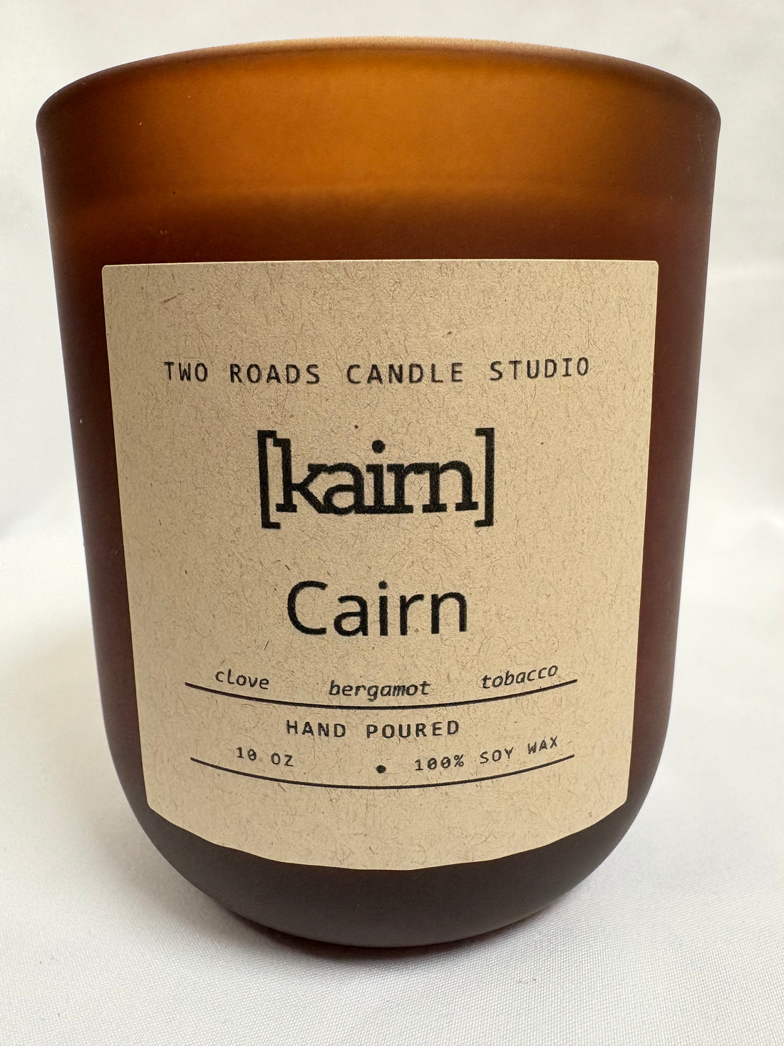 Candle with a label from Two Roads Candle Studio on a white background